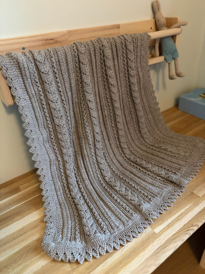 Lys beige Ingrid-babyteppe henger over et trestativ ved siden av en kosekanin.